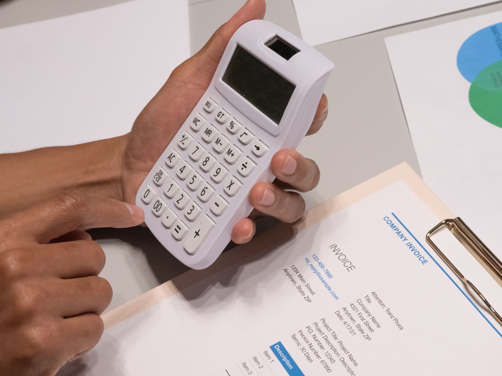 Hand using a calculator over an invoice